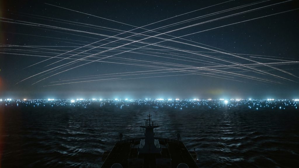 夜の大西洋を船の光点と衛星軌道が覆うイメージ